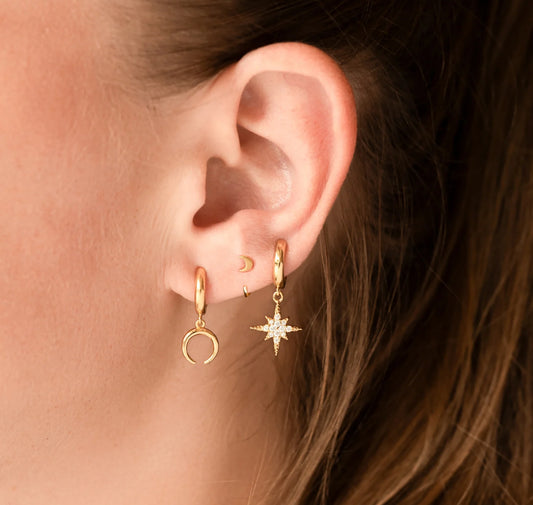 A pair of gold-colored hoop earrings with a textured surface in ear