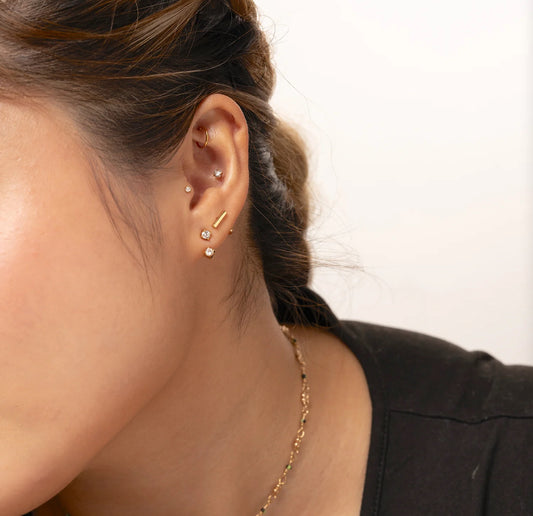A pair of gold-colored stainless steel hoop earrings with a sleek finish in ear.