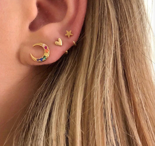 A pair of gold-colored stainless steel hoop earrings with three star-shaped cutouts in ear