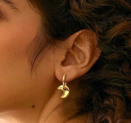 A pair of gold-colored stainless steel hoop earrings with a textured surface, in ear