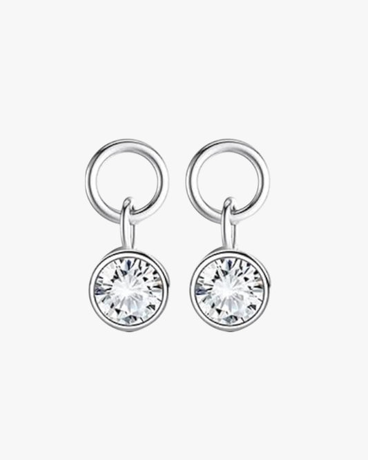 A pair of silver-colored hoop earrings with a silver inner diameter, featuring a central cubic zirconia surrounded by smaller clear crystals.