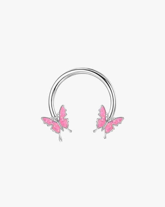 A silver-colored hoop earring with two pink butterfly designs on it, against a white background.