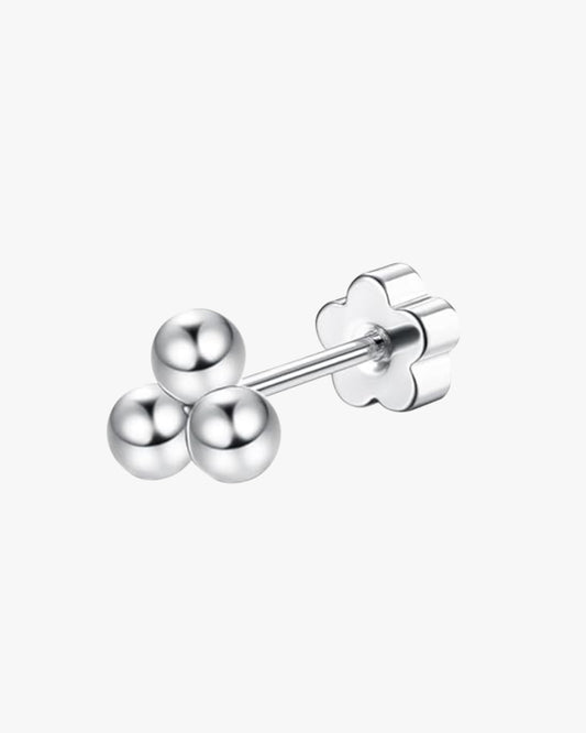 A double-headed trinity stud earring with a silver-colored titanium bar and three gold-colored spherical embellishments.