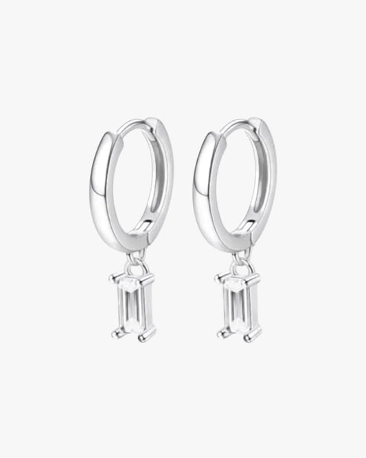 A pair of silver hoop earrings with small clear crystal pendants.