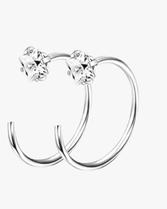 A pair of silver-colored stainless steel hoop earrings with clear crystal embellishments.
