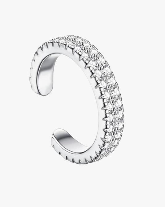 A silver cuff with zirconia stones set in a solid pattern, with a brass finish