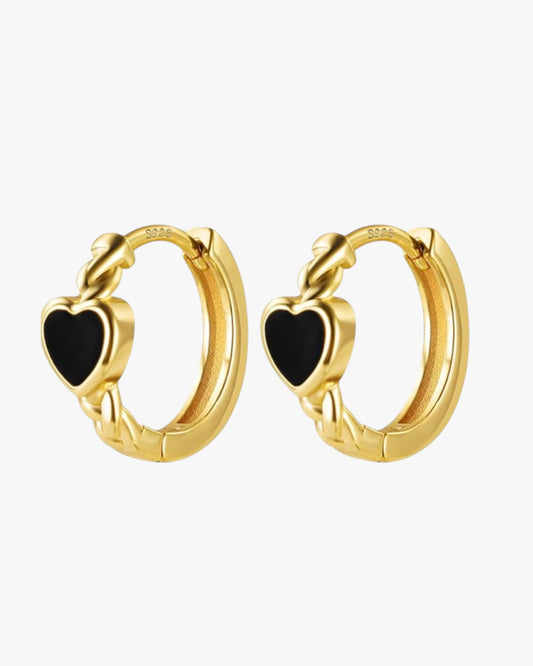 A pair of gold-colored hoop earrings with black heart-shaped details on the hoops.