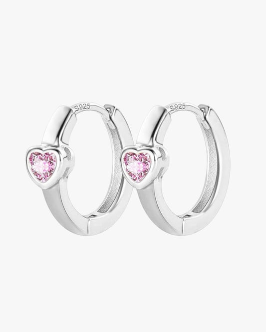 A pair of silver-colored hoop earrings with purple heart designs on them.