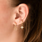 A pair of gold-colored hoop earrings with a textured surface in ear