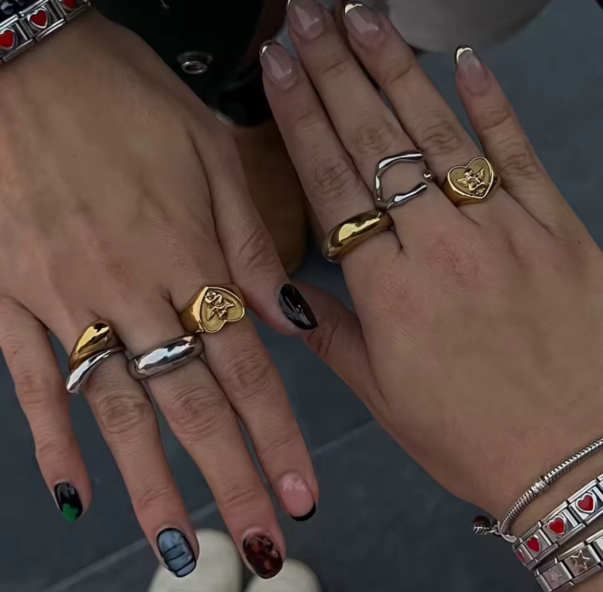 Close-up of two hands wearing multiple rings with various designs.
