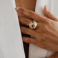 Gold ring on a person's finger with a plain background
