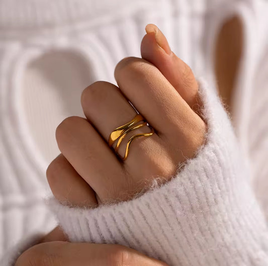 Gold ring on a finger with a white textured background
