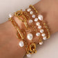 Gold chain and pearl bracelet on a wrist against a neutral background