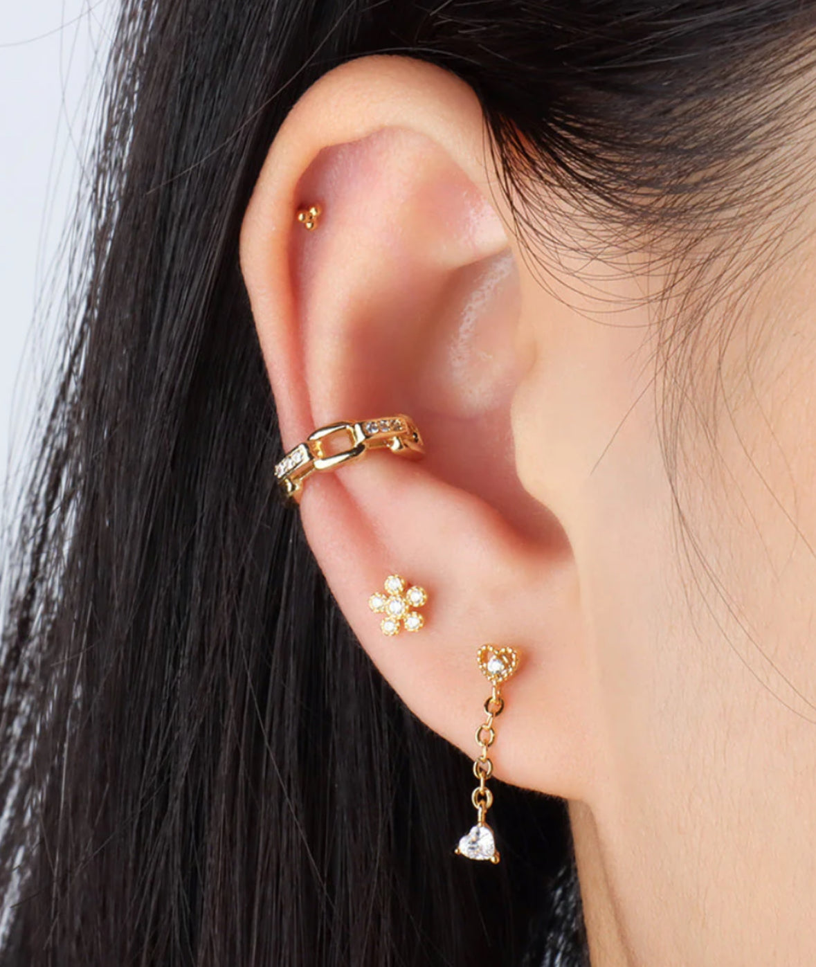 A pair of gold-colored stainless steel earrings with a geometric design, featuring three spherical elements connected by a central point in ear
