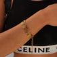 Gold chain bracelet on a person wearing a black and white Celine bikini.