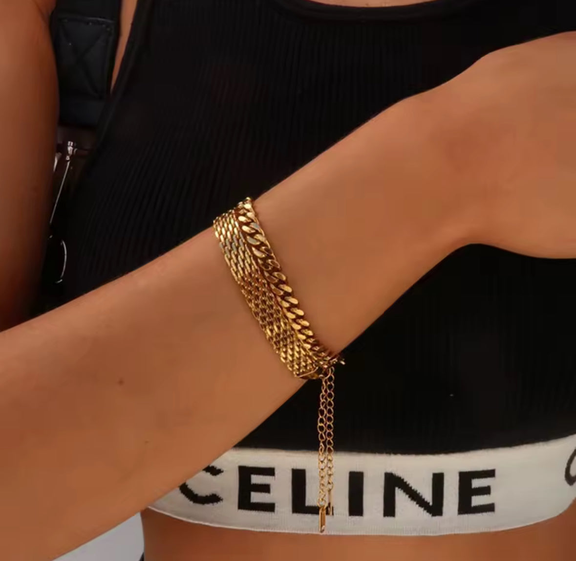 Gold chain bracelet on a person wearing a black and white Celine bikini.