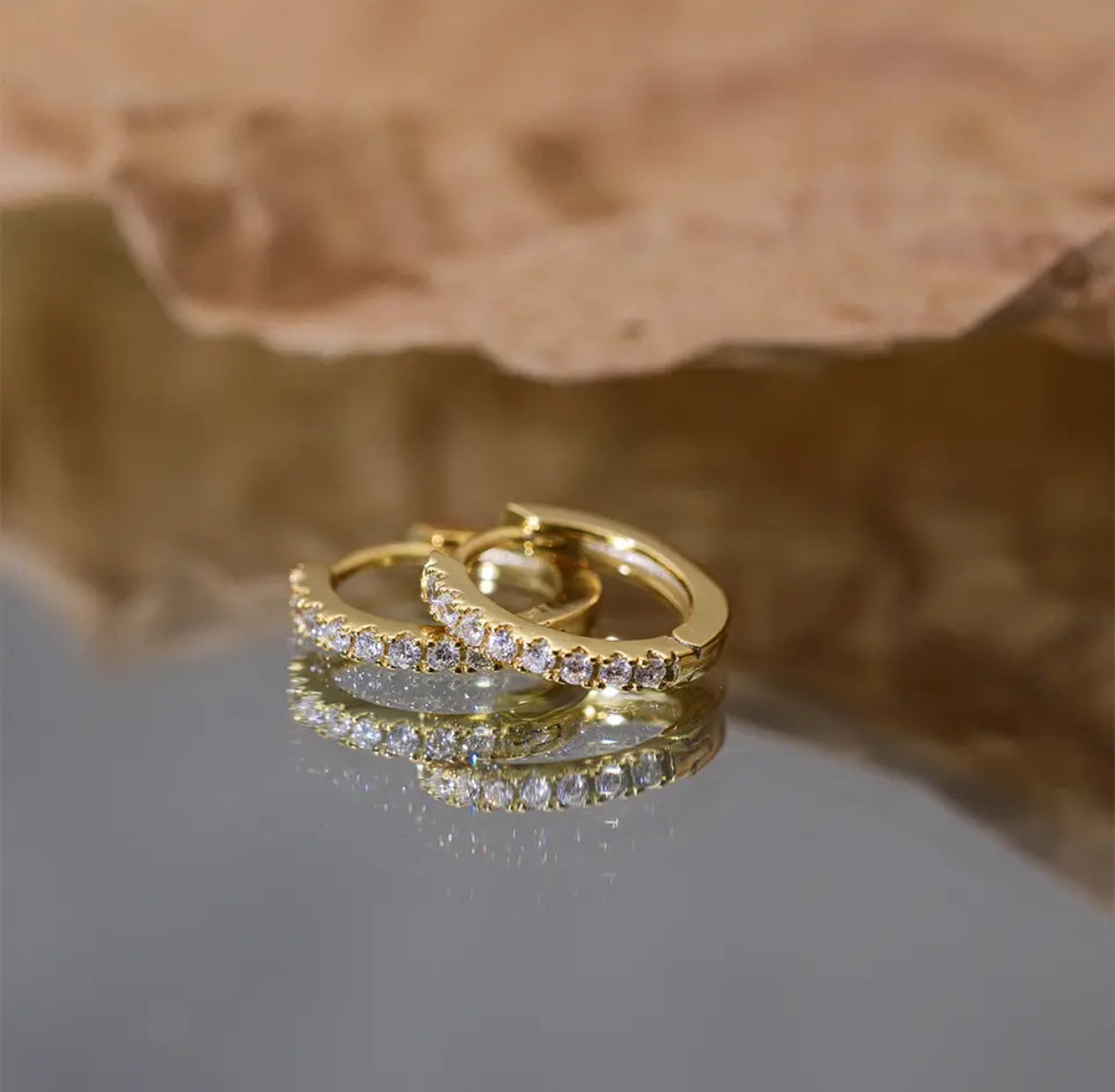 "Image: Gold pave hoops, radiating timeless elegance on a mirror