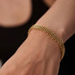 Gold bracelet on a wrist against a black background