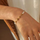 Gold and pearl bracelet on a wrist with a neutral background