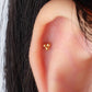 A pair of gold-colored stainless steel earrings with a geometric design, featuring three spherical elements connected by a central point in ear