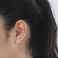 Close-up of an ear with gold earrings against a neutral background