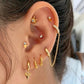 A double gold-colored stud earring with a clear gemstone in ear.