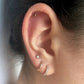 A pair of gold-colored stainless steel ball stud earrings in ear