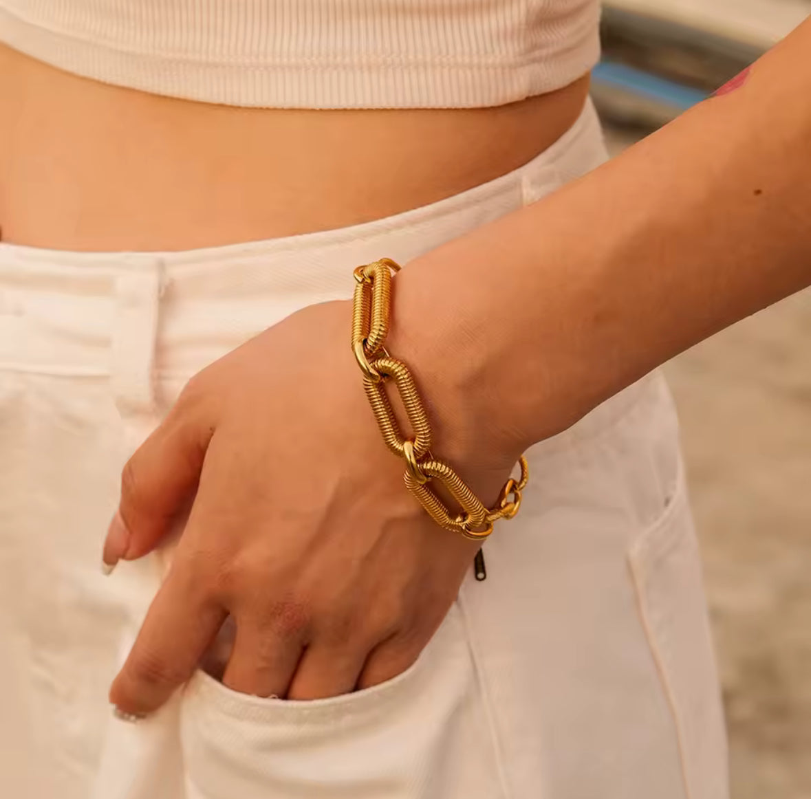 Gold chain bracelet on a wrist with a blurred background