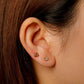 Close-up of an ear with two earrings: a small stud and a double-stud earring.