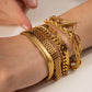 Gold bracelets on a wrist with a neutral background