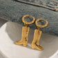Gold cowboy boot earrings on a white dish with denim background