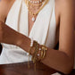 Close-up of a person's arm wearing multiple gold and pearl bracelets and necklaces.