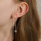 A pair of gold-colored stainless steel earrings with star-shaped embellishments at the end of each strand in ear