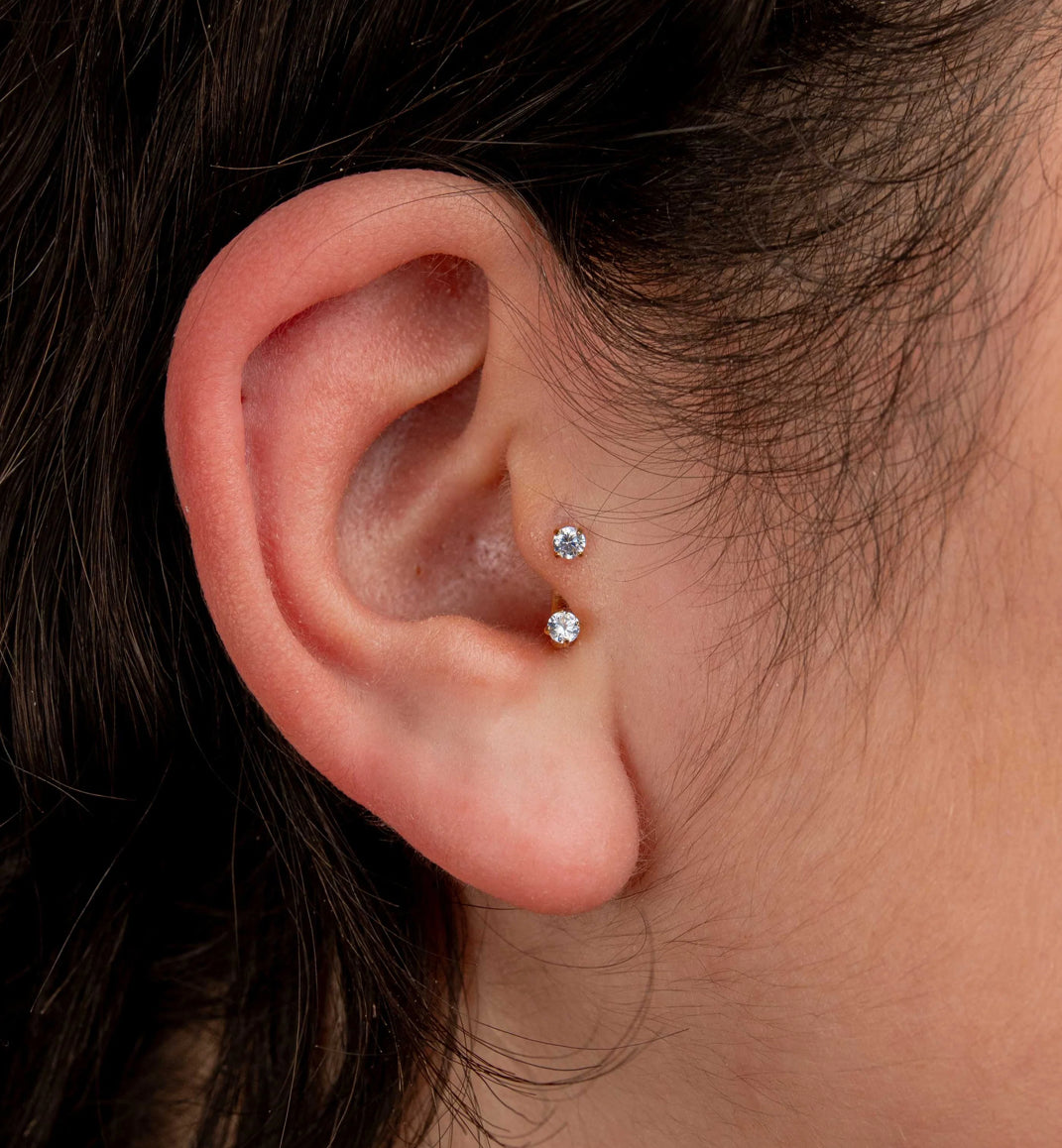 Close-up of an ear with two diamond stud earrings.