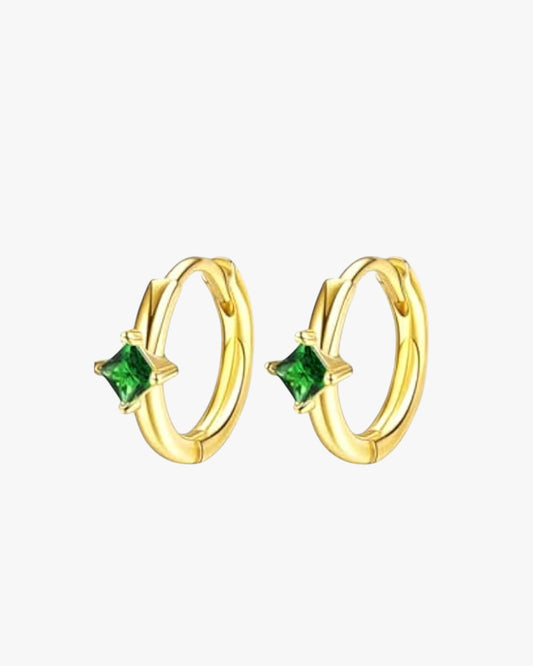 Gold hoop earrings with green gemstones on a white background