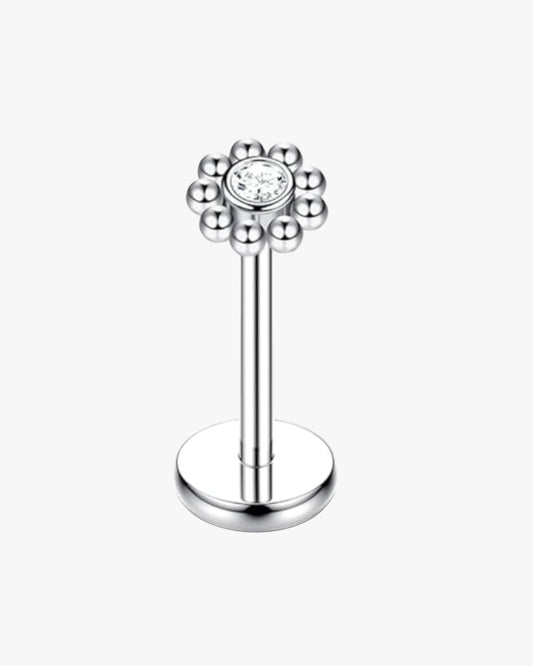 Silver lip ring with a floral design and clear gemstone on a white background