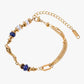 Gold stainless steel 18k gold pvd plated bracelet with blue and white beads on a white background