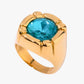 Gold 18K plated stainless steel ring with a blue gemstone on a white background 