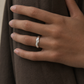 Hand wearing a silver ring with a brown fabric background