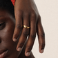 Close-up of a hand with a gold ring on a neutral background
