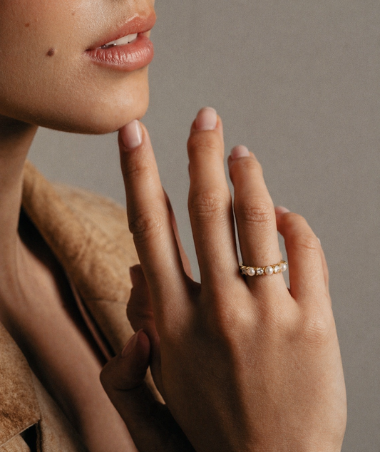 Close-up of a hand with a ring on a neutral background