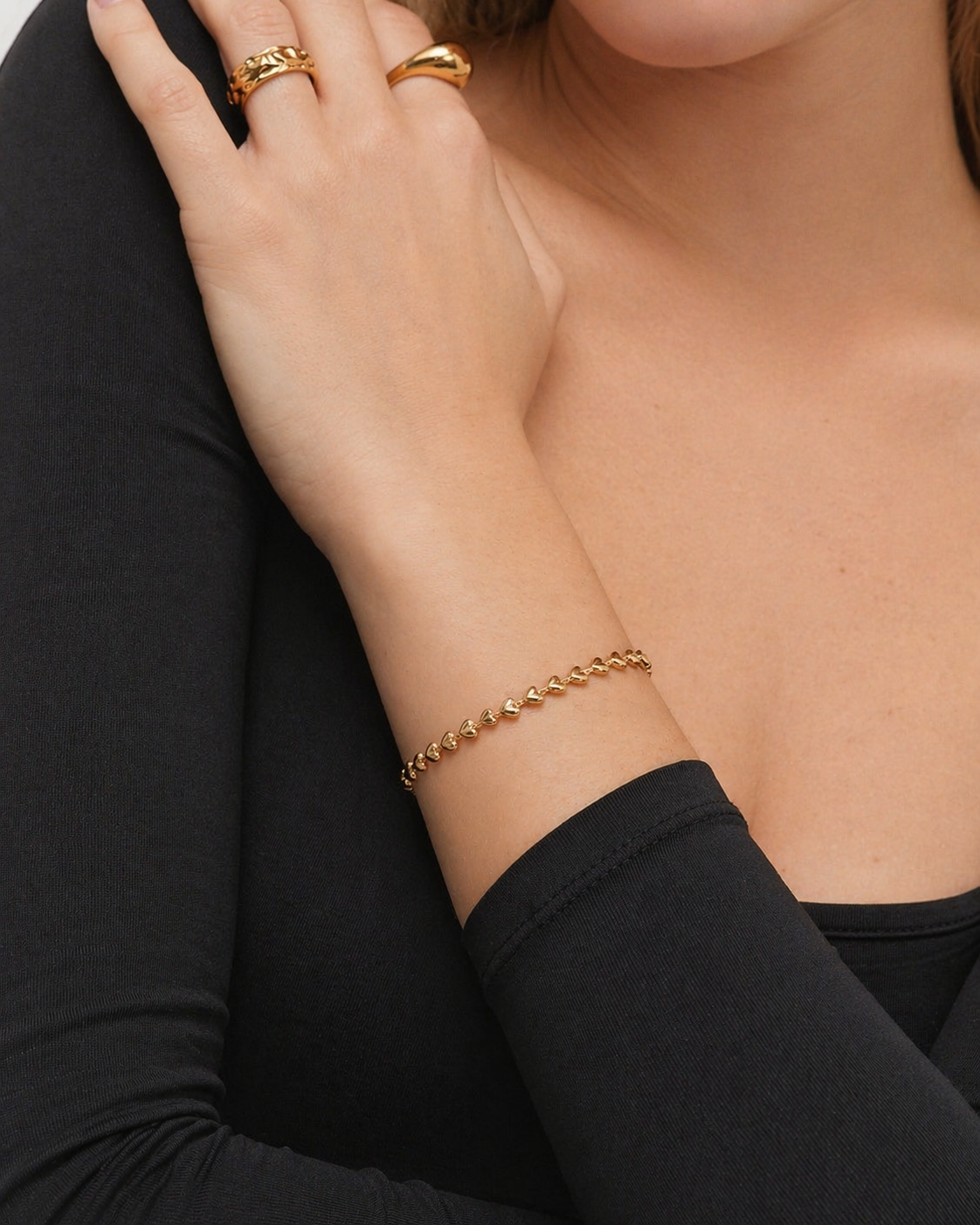 Gold bracelet on a person's wrist with a black sleeve