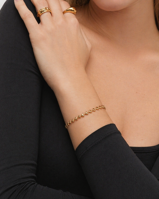 Gold bracelet on a person's wrist with a black sleeve