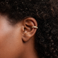 Close-up of an ear wearing a gold earring with a dark background