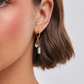 Close-up of a gold earring with gemstones worn by a person.