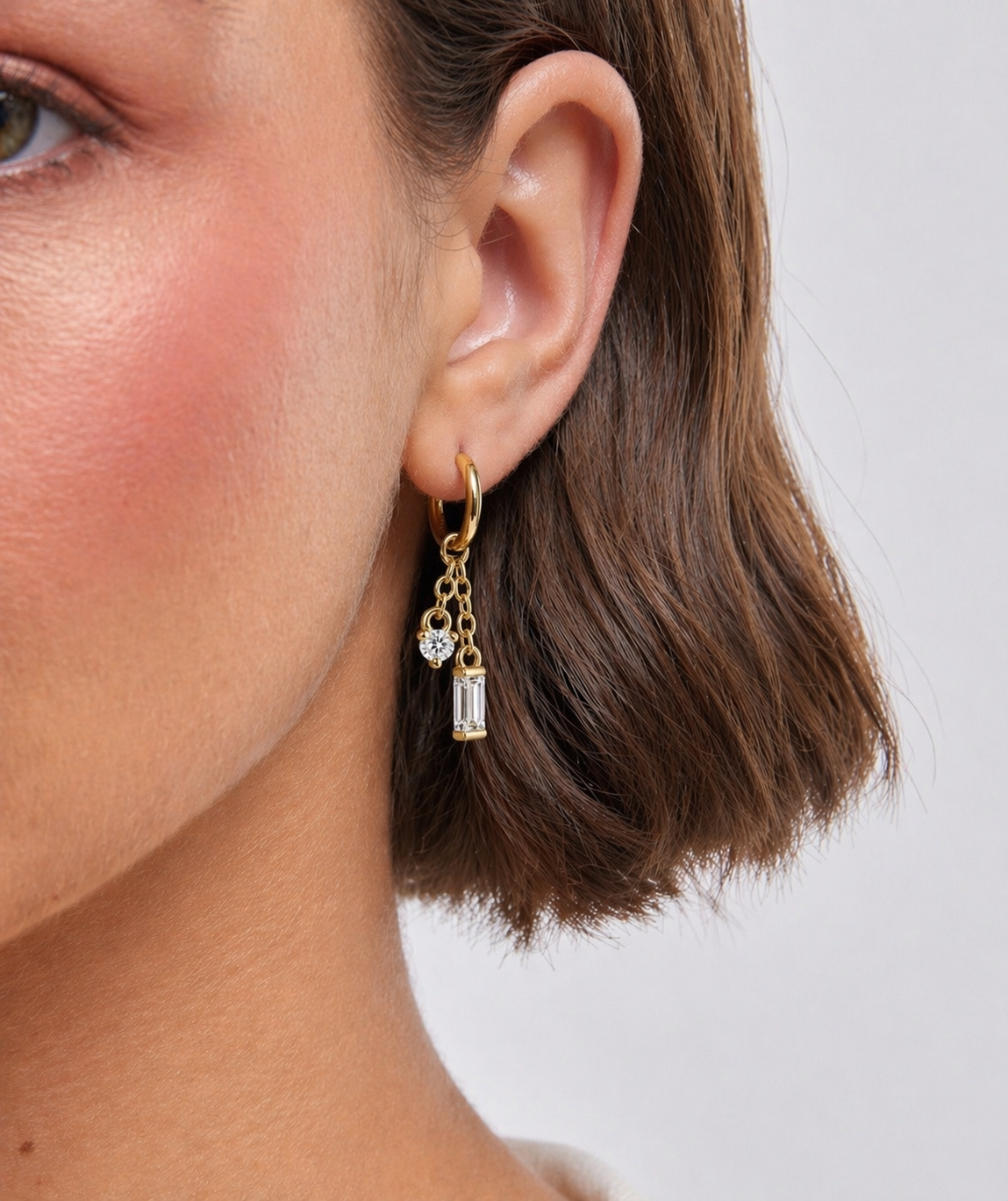 Close-up of a gold earring with gemstones worn by a person.