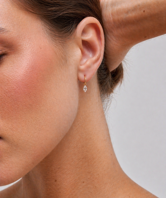 Close-up of a woman wearing a diamond earring with a plain background