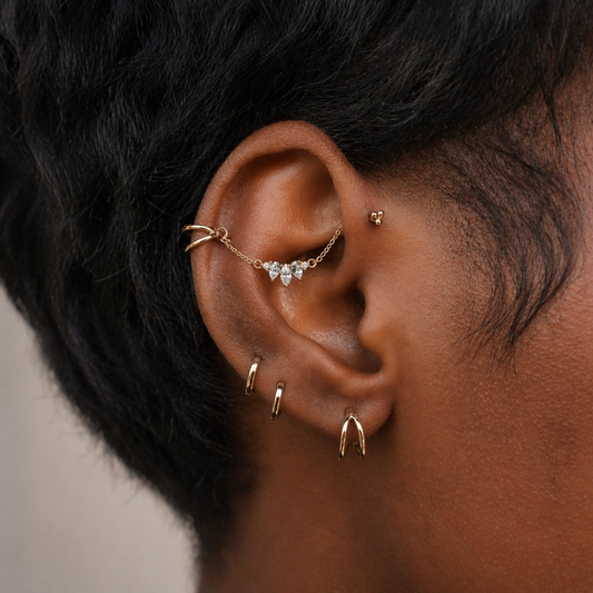 Close-up of an ear with gold earrings on a blurred background