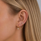 Close-up of an ear wearing gold earrings with small diamonds.