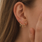 Close-up of an ear wearing gold star-shaped earrings with a blurred background